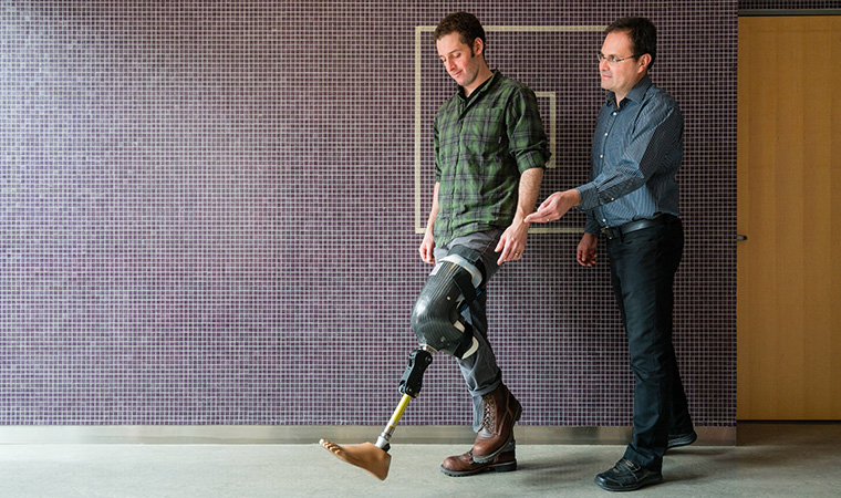 Professor Jan Andrysek and a grad student demonstrate a lower-limb prosthetic device. 