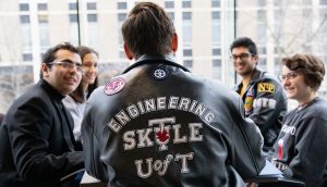 Students in SKULE jackets converse around a table in the Bahen Centre.