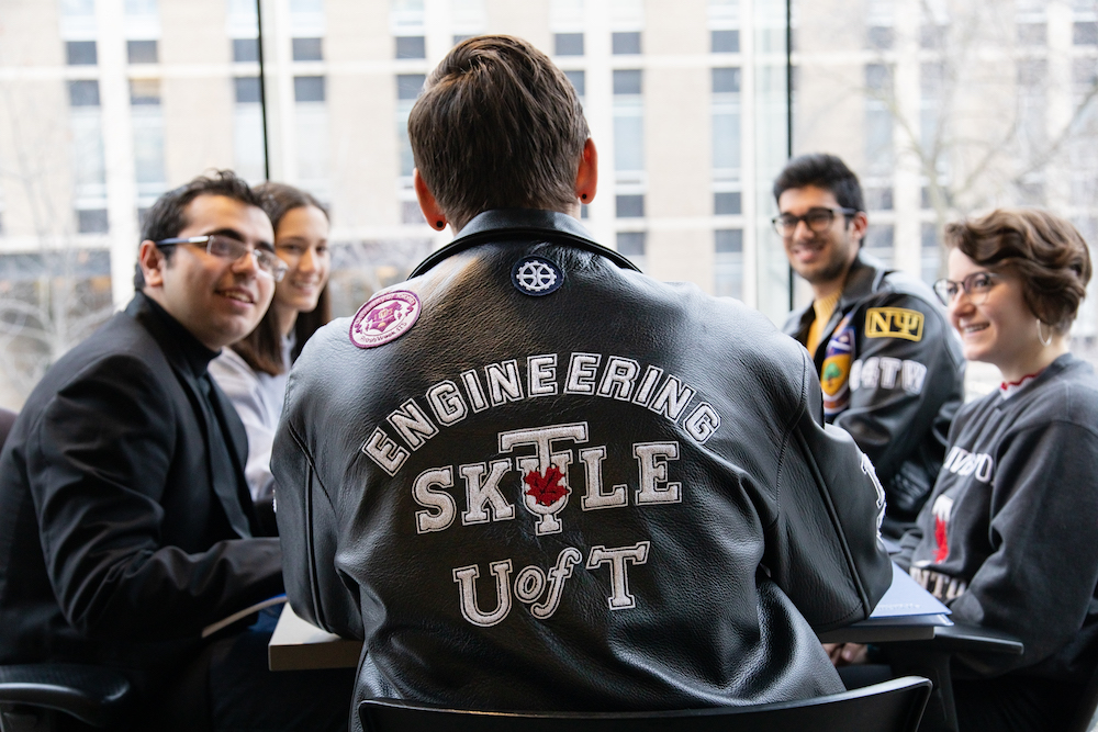 Students in SKULE jackets converse around a table in the Bahen Centre.